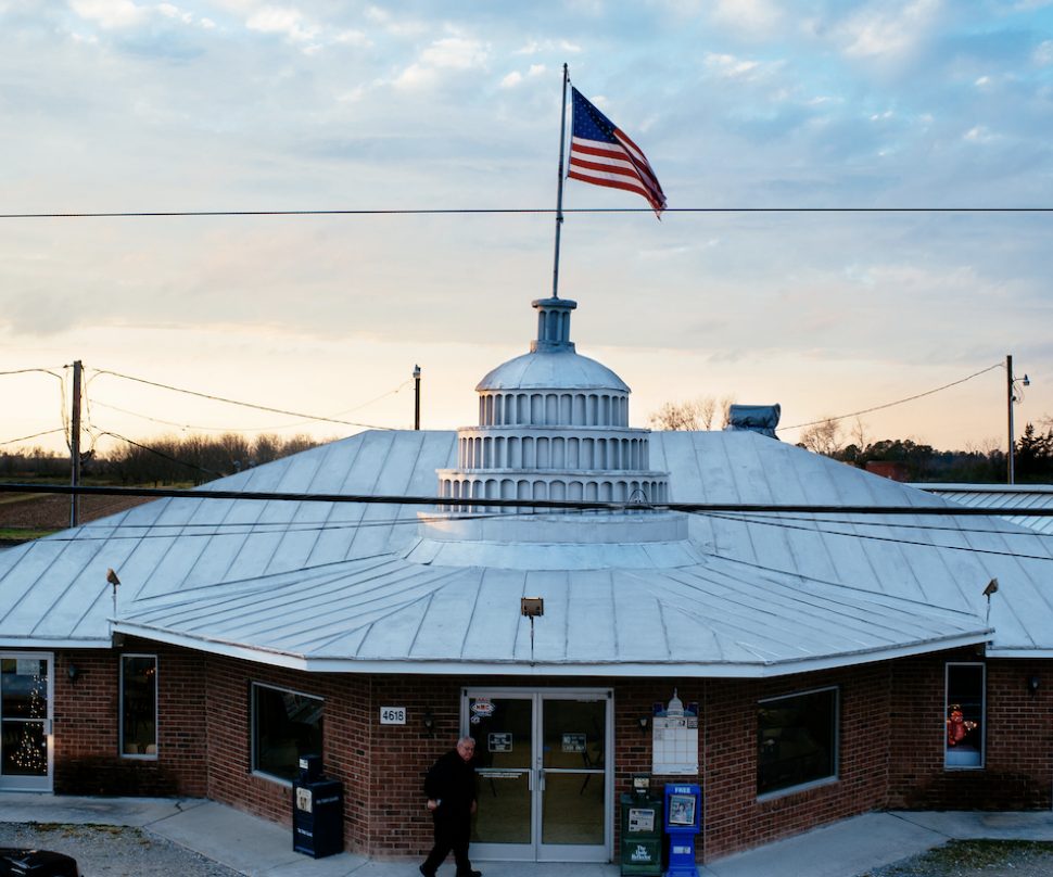 Round brick exterior of Skylight Inn BBQ in Ayden with American flag overhead